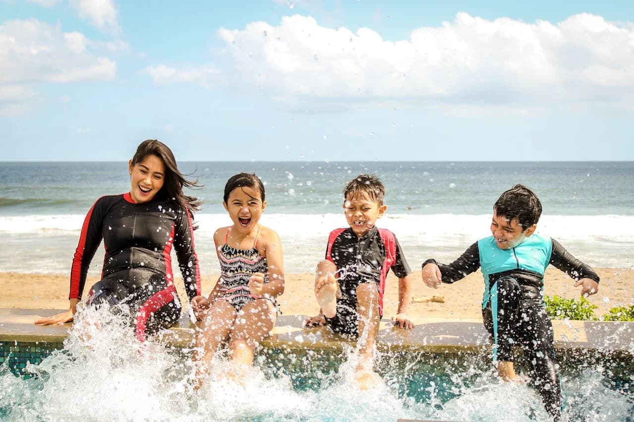 A young woman and children splashing in a seaside pool